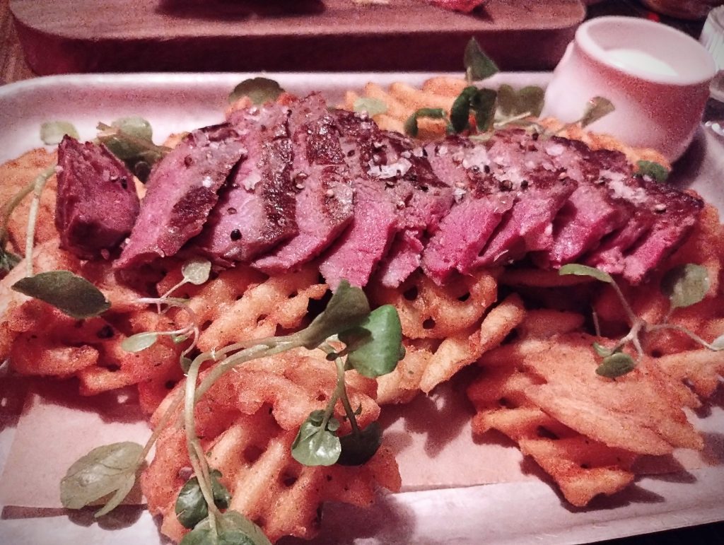 Photo: sliced steak over a pile of waffle fries. Watercress. Lots of sea salt and cracked black pepper.